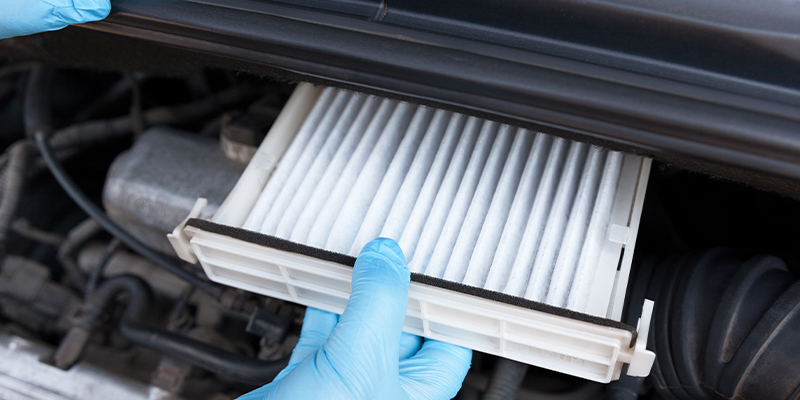 A service technician replacing a vehicle's air filter with a new, clean air filter.