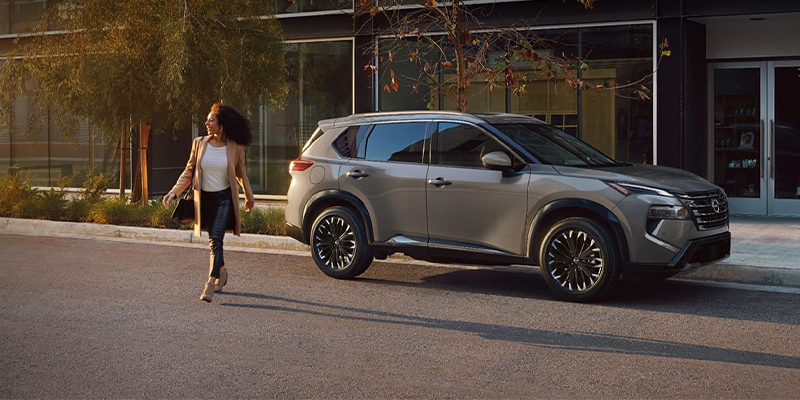 The driver walking away from their silver Nissan Rogue parked on a city street.